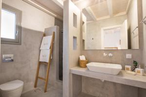 a bathroom with a sink and a toilet and a mirror at CIEL BOUTIQUE VILLAS in Afiartis +33 photos