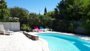 a backyard with a swimming pool and chairs next to a fence at VILLA ESTEREL in Saint-Raphaël
