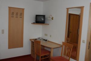 Pokój z biurkiem i telewizorem na ścianie w obiekcie Hotel Garni Sonnenheim w mieście Fiss