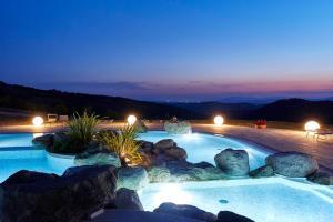 una grande piscina con rocce in un cortile posteriore di notte di Fattoria La Pieve a Stribugliano