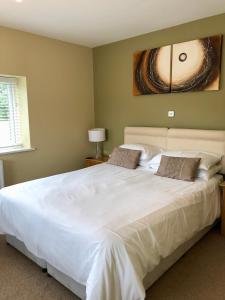 a bedroom with a large white bed with a painting on the wall at Emlyn Arms in Llanarthney