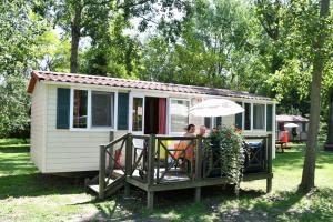 uma mulher sentada numa mesa numa casa pequena em Balatontourist Berény Naturist Camping em Balatonberény