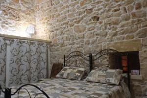 a bedroom with a bed and a stone wall at i Caseddhi di Santo e Totò in Torre Suda