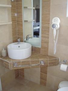 a bathroom with a sink and a mirror and a phone at Nostos Hotel in Afitos