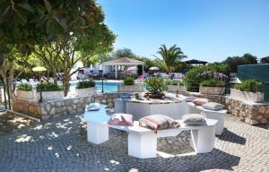 a patio with white tables and pillows and a pool at CASA BEACHCOMBER Le jardin des Arts in Lagos