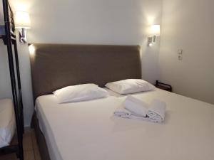 białe łóżko z dwoma białymi ręcznikami w obiekcie Delfini Hotel w Pireusie