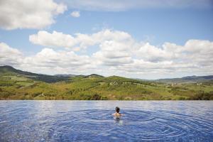 une personne nageant dans une grande masse d'eau dans l'établissement Castello di Casole, A Belmond Hotel, Tuscany, à Casole dʼElsa