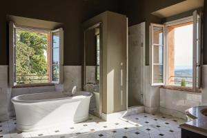 a bathroom with a tub and a toilet and windows at Castello di Casole, A Belmond Hotel, Tuscany in Casole dʼElsa