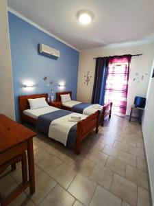 a bedroom with two beds and a table and a window at Corfu Sunflower Apartments in Benitses