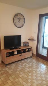 a living room with a tv and a clock on the wall at Appartement Le Corail in Cap d'Agde
