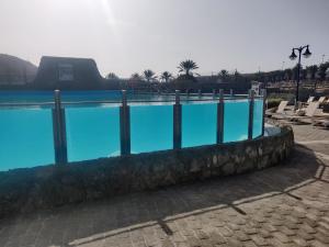 une grande piscine avec des chaises et une clôture dans l'établissement Casa Holmston, Duplex villa with hot tub in Anfi Tauro Topaz, à Mogán