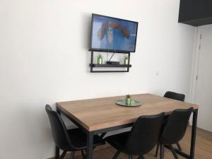 a wooden table with chairs and a television on a wall at FLORIDE in Knokke-Heist