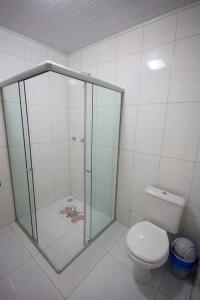 y baño con ducha de cristal y aseo. en Pousada Mama Pereira, en Japaratinga