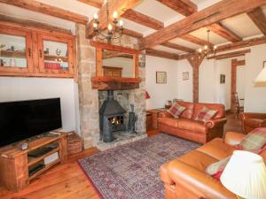 a living room with a fireplace and a television at Lees Moor Cottage in Matlock