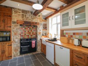 a kitchen with wooden cabinets and a stone wall at Lees Moor Cottage in Matlock