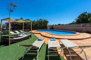 a backyard with a swimming pool with chairs and an umbrella at Sa Carroca Villa in Sant Josep de sa Talaia