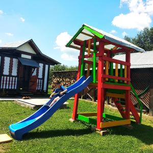 a child sitting on a slide on a playground at "Різьб'ярська садиба" in Slavske