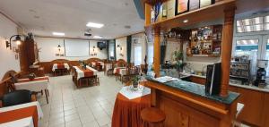 un restaurante con bar y algunas mesas y sillas en Hotel Baross, en Győr