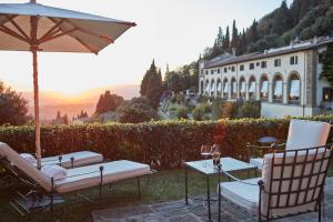 un tavolo e sedie con ombrellone e un edificio di Villa San Michele, A Belmond Hotel, Florence a Fiesole