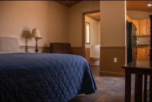 a bedroom with a blue bed and a kitchen at Tumbleweed Lodge - No Smoking, No Pets in Monahans
