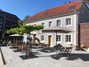 a group of tables and chairs with umbrellas in front of a building at Gasthof Alter Markt in Losheim