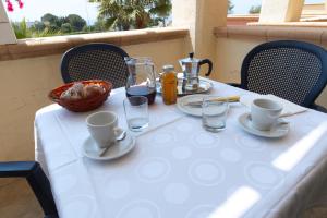 un tavolo con una tovaglia bianca con tazze e bicchieri di Villaggio Resort Arco Del Saracino a Lido Marini
