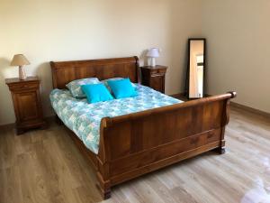 a bedroom with a wooden bed with blue pillows at Fermette 3ch - 6p au pays du coquelicot by La Source d'OrFée in Courcelette