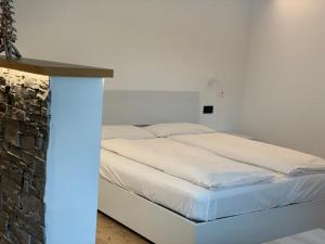 ein Schlafzimmer mit einem weißen Bett und einer Steinmauer in der Unterkunft Chalet dal Grant in Livigno