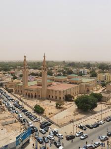 un grand bâtiment avec des voitures garées dans un parking dans l'établissement Al Khaima City Center, à Nouakchott