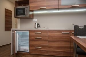 eine Küche mit Holzschränken und einer Mikrowelle in der Unterkunft Fresh in Veľký Meder