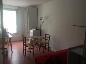 - un salon avec une table, des chaises et un réfrigérateur dans l'établissement B&B Mimi Totem, à Villeurbanne