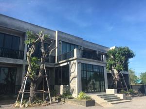 un edificio con un árbol delante de él en Bosston Hotel en Phetchaburi