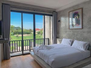 a bedroom with a large bed and a balcony at Bosston Hotel in Phetchaburi