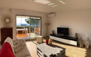 a living room with a couch and a flat screen tv at Superbe 2P vue mer, ensoleillé, piscine in Roquebrune-Cap-Martin