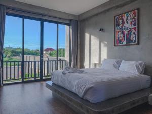 a bedroom with a large bed and a balcony at Bosston Hotel in Phetchaburi