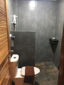 a bathroom with a toilet and a tiled wall at Bosston Hotel in Phetchaburi