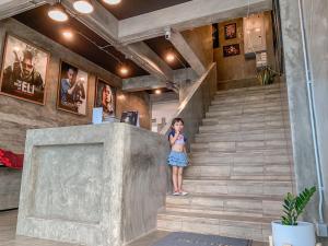 a girl standing on a staircase in a building at Bosston Hotel in Phetchaburi
