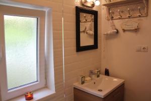 een badkamer met een wastafel, een spiegel en een raam bij La Bella in Sibiu