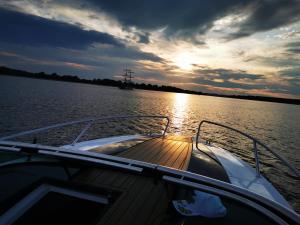 a boat on the water as the sun sets at Avanti Resort Mikołajki , w centrum przy jeziorze i promenadzie, śniadanie i obiad lub obiadokolacja w cenie in Mikołajki