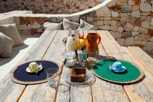 drewniany stół z talerzami jedzenia i napojów na nim w obiekcie Trulli di Mezza w mieście Cisternino