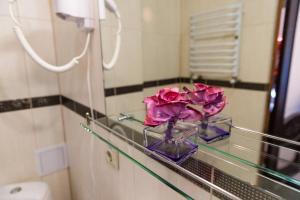 Eine Vase mit Blumen steht auf einem Glasregal im Badezimmer. in der Unterkunft Hotel Lubych in Brody + 43 Fotos