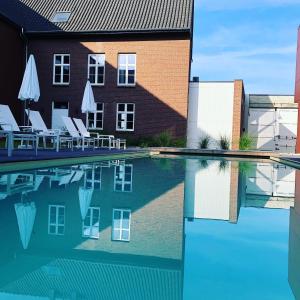 a swimming pool with chairs and a building at Hof van Stayen in Sint-Truiden