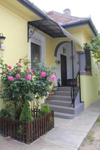 una casa amarilla con flores rosas en las escaleras en La Bella en Sibiu