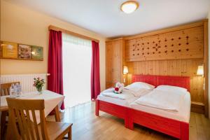 Schlafzimmer mit einem roten Bett und einem Tisch in der Unterkunft JUFA Hotel Tieschen in Tieschen