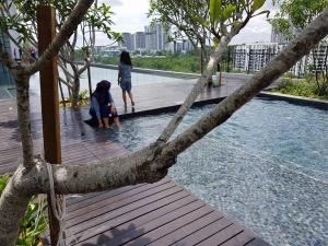 dos mujeres de pie en un paseo de madera cerca del agua en MyCozySOHO with Excellent Swimming Pool View en Cyberjaya