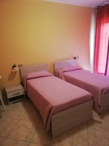 two beds in a room with pink sheets at Agriturismo solare in Perito