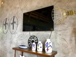 a wall with a tv and three vases on a table at Rosa Chá in Santo Amaro