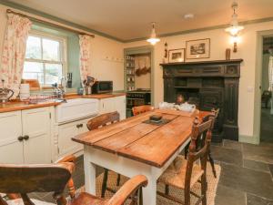 a kitchen with a wooden table and a fireplace at Faldarroch Farm in Newton Stewart