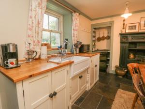 a kitchen with white cabinets and a wooden counter top at Faldarroch Farm in Newton Stewart