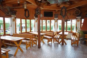 un restaurante con mesas de madera, bancos y ventanas en Penzion Terasa, bed & breakfast, en Velké Losiny